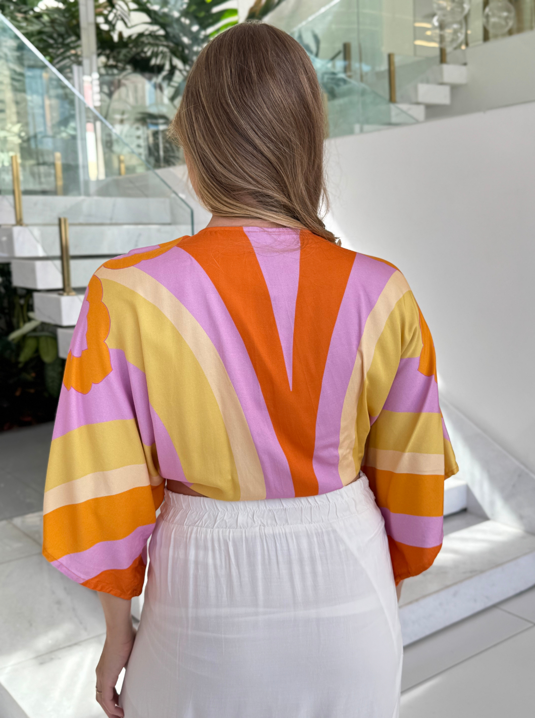 FARM Aurora Blusa featuring vibrant floral patterns and a relaxed fit, displayed on a hanger against a neutral background.