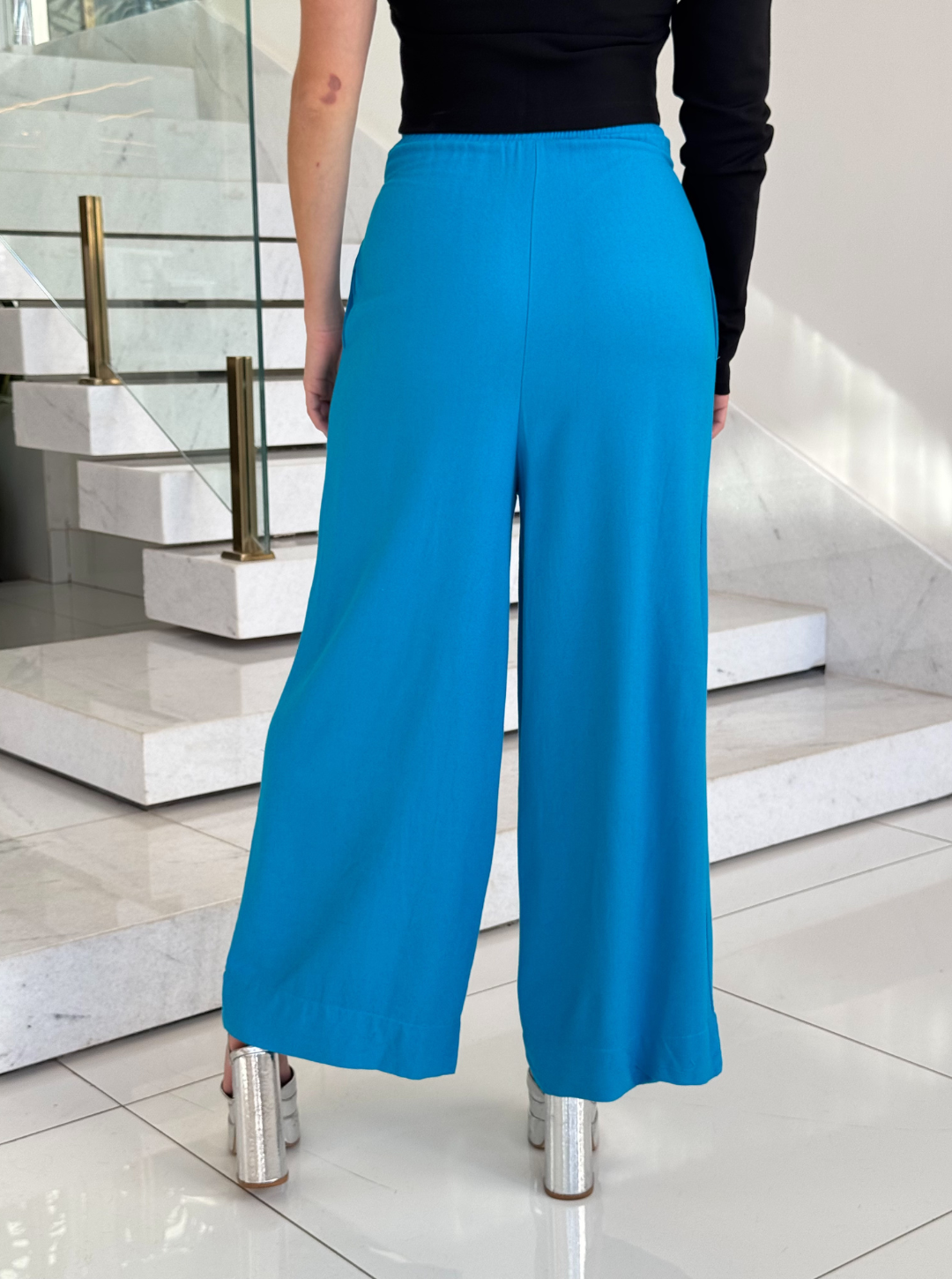 Calça pantalona de alfaiataria da FARM, com caimento elegante e tecido fluido em fundo neutro.