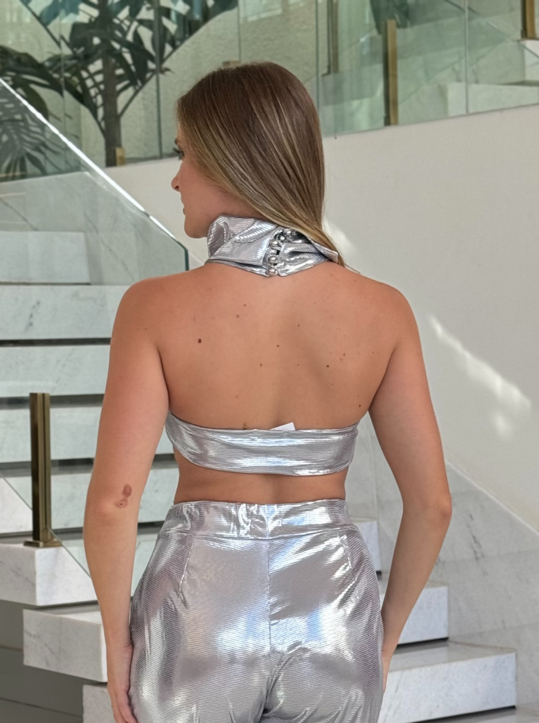 Blusa prateada Lopz Versini, feita de tecido brilhante, com detalhes elegantes e corte moderno, vista de frente.
