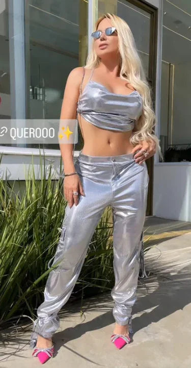 Calça metalizada prata Lopz, estilo moderno, feita de tecido brilhante, ajustada na cintura, usada por uma modelo.